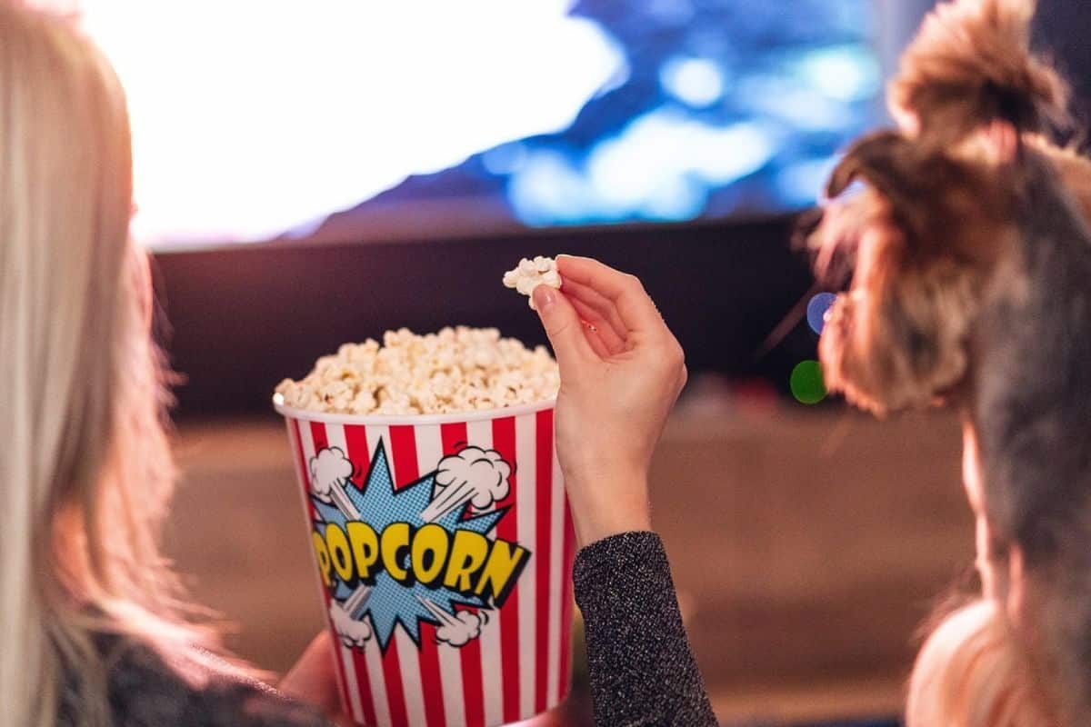 Une femme qui mange des popcorns à côté d'un chien